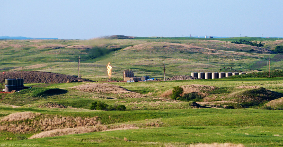 Fracking well pad and gas flare in Bakken district, North Dakota, with gas flare.